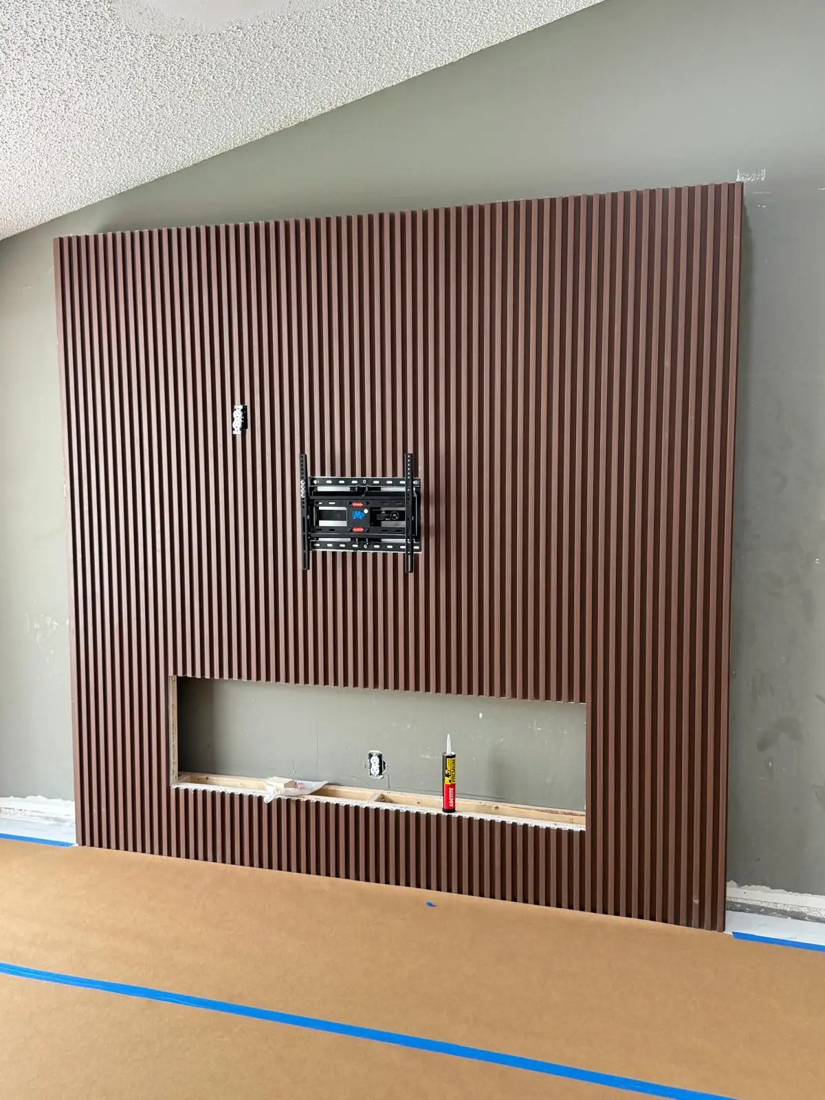 A custom slatted feature wall with a TV mount and recessed area.