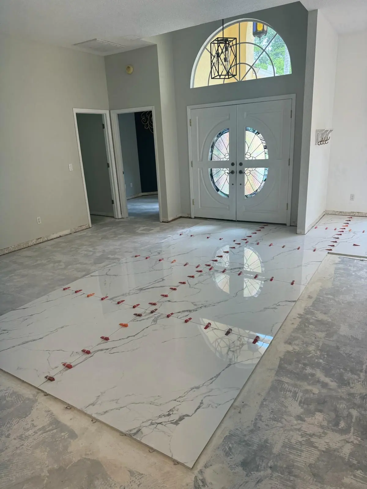 A spacious room with a marble floor installation in progress.